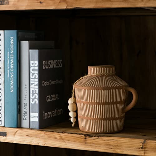 Books and a ceramic vase on a wooden shelf.