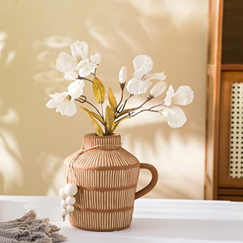 Ceramic vase with white flowers on a table.