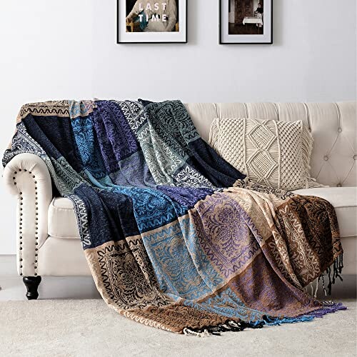 A multicolored patterned throw blanket draped over a white sofa with decorative cushions.