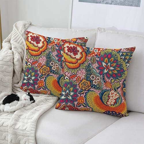 Colorful floral throw pillows on a sofa with a blanket and a plush toy.