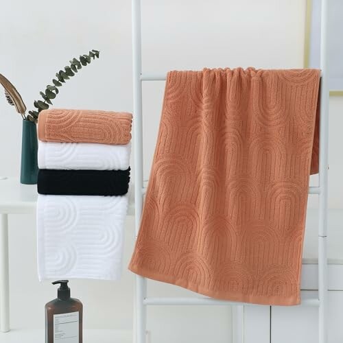 Textured towels in various colors on a rack with a plant and soap bottle nearby.