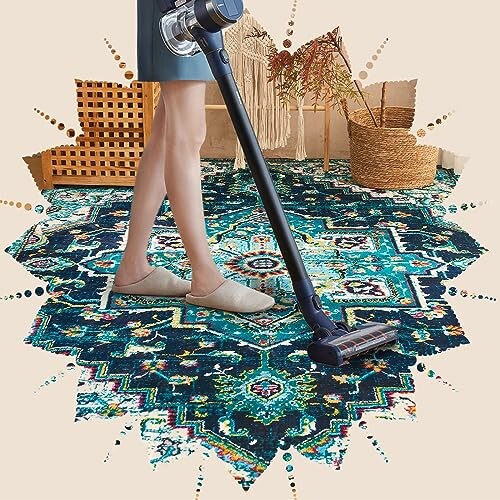 Person vacuuming a vibrant patterned rug with a cordless vacuum.